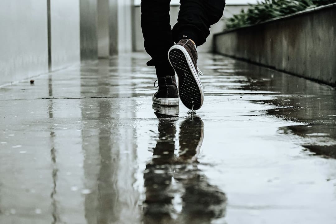 雨の中を歩く黒い靴の男性