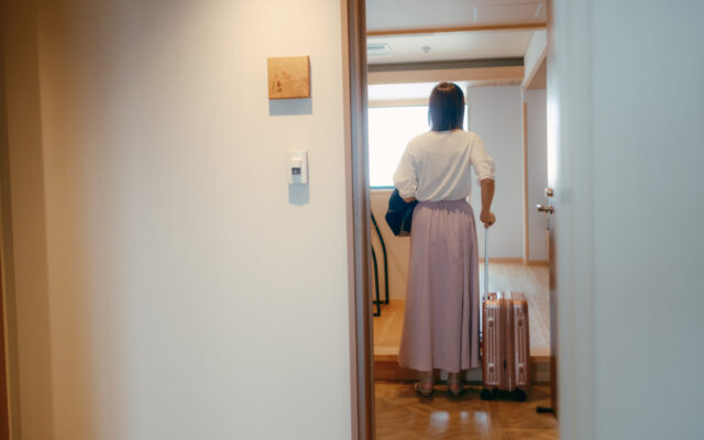 20代女性がホテルの客室に入るシーン