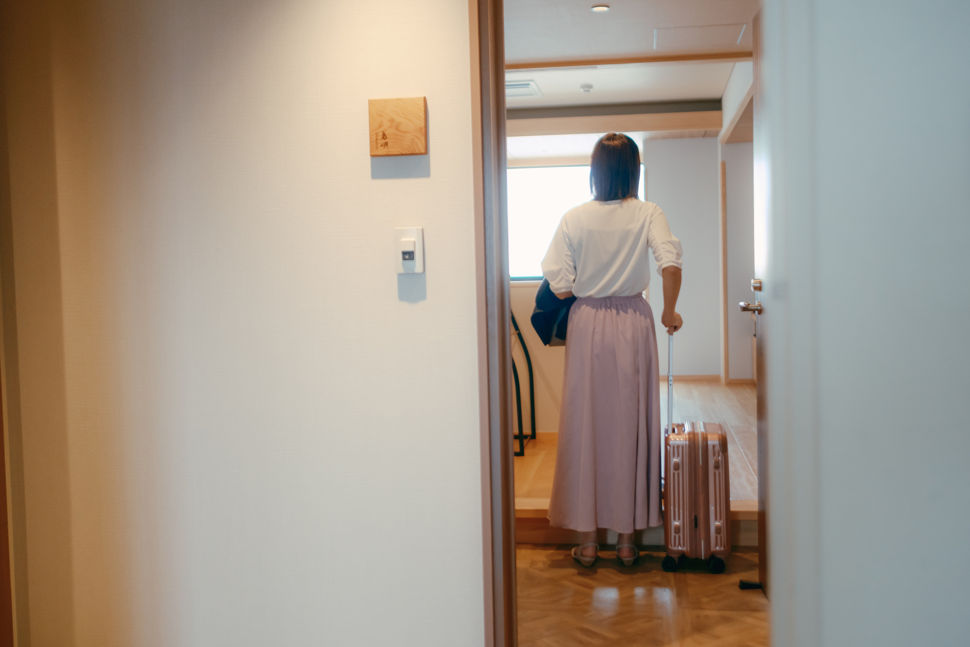 20代女性がホテルの客室に入るシーン
