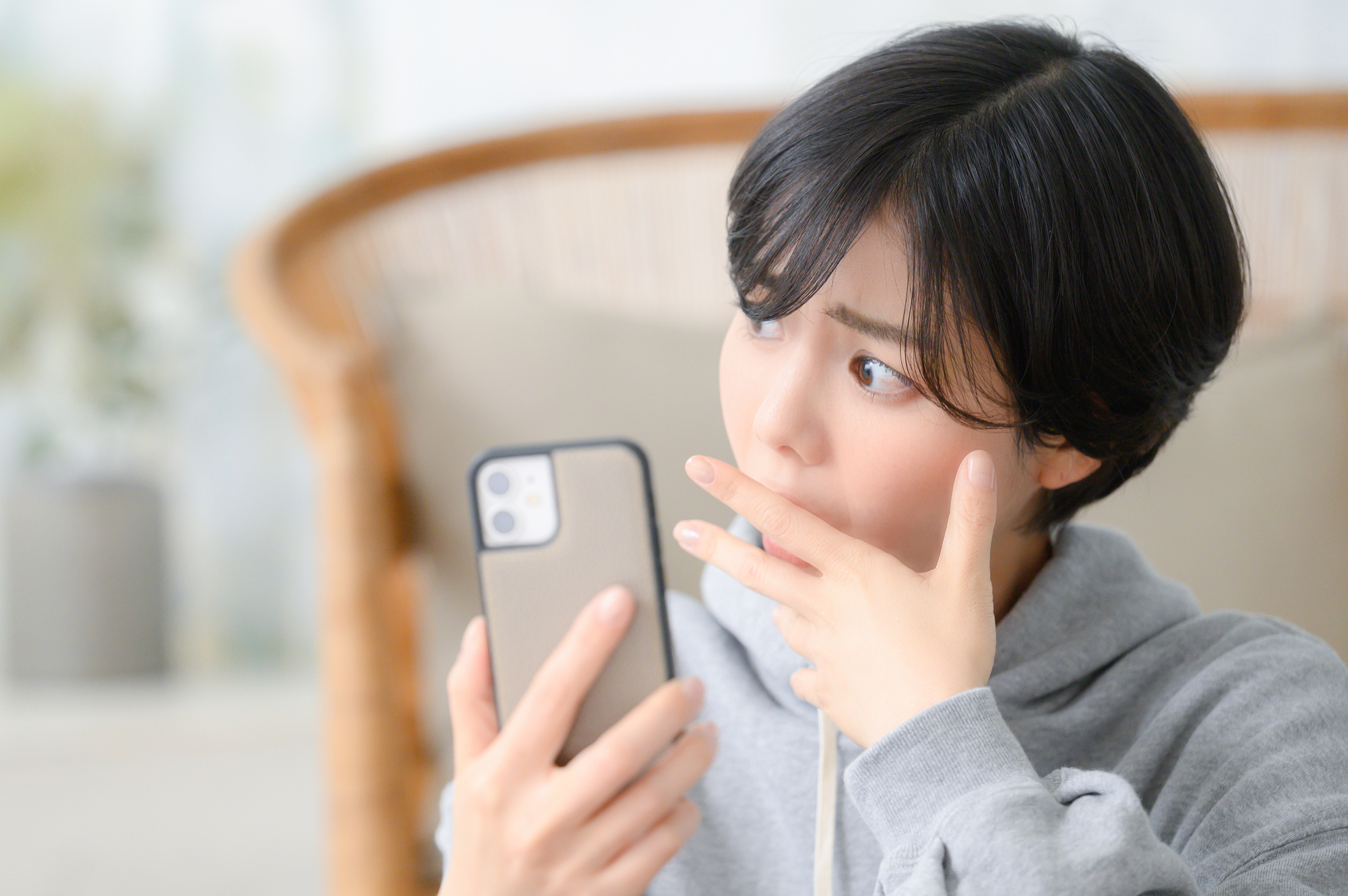 スマホを持ち考える女性