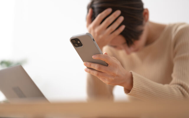 スマホ持って悩んでいる女性
