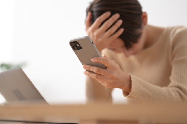 スマホ持って悩んでいる女性