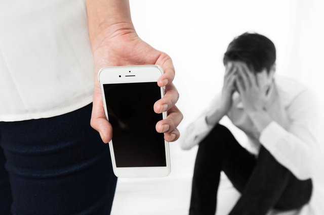 スマホを持つ女性と悩む男性