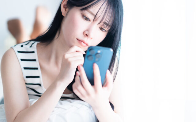 スマートフォンを持ち悩む女性