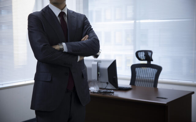 腕を組んでいるスーツ姿の男性