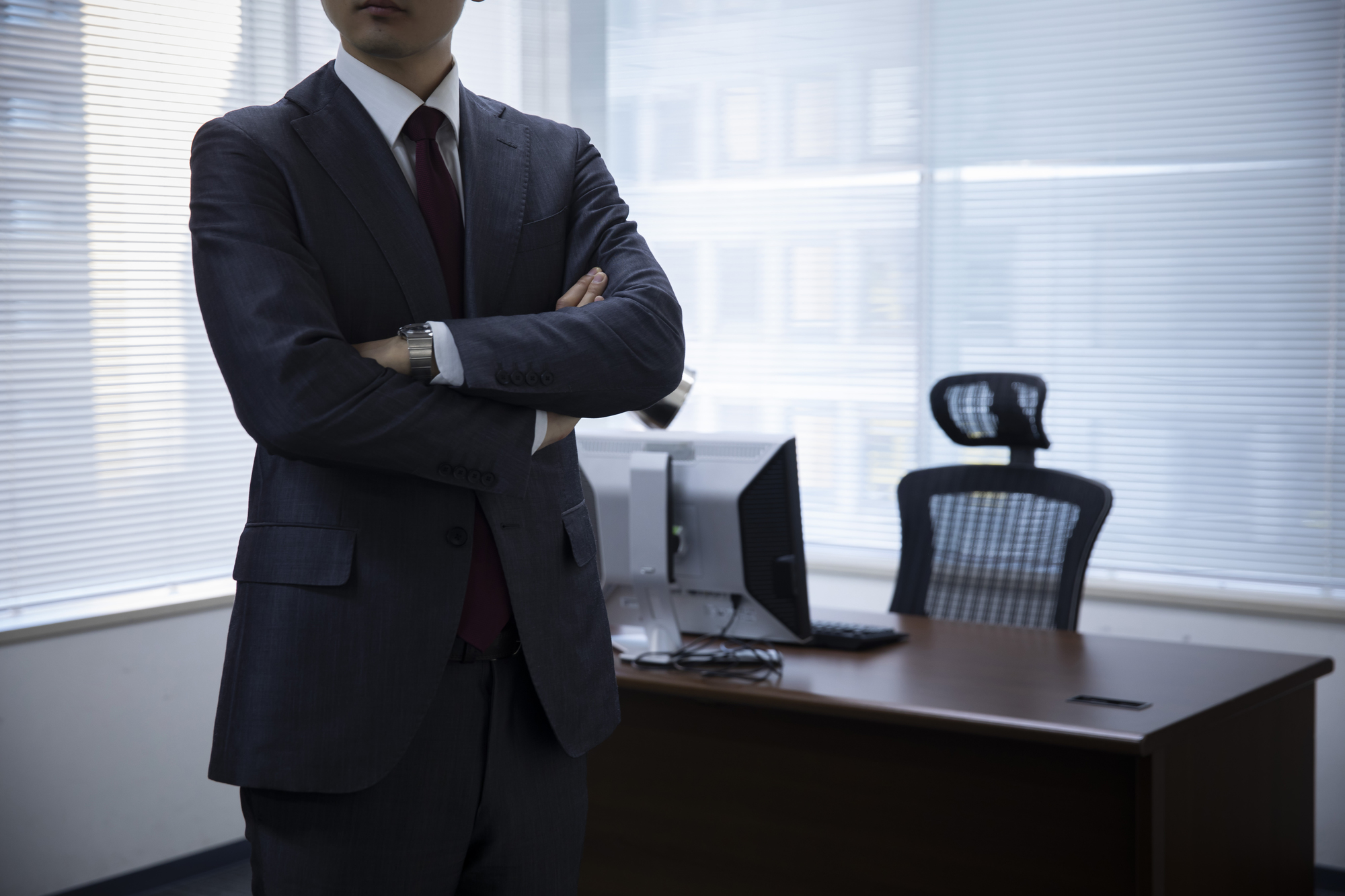 腕を組んでいるスーツ姿の男性